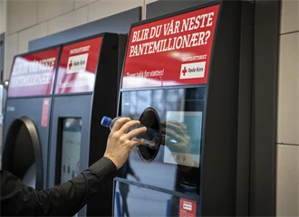 En hånd strekker seg mot pantemaskinen for å pante en flaske