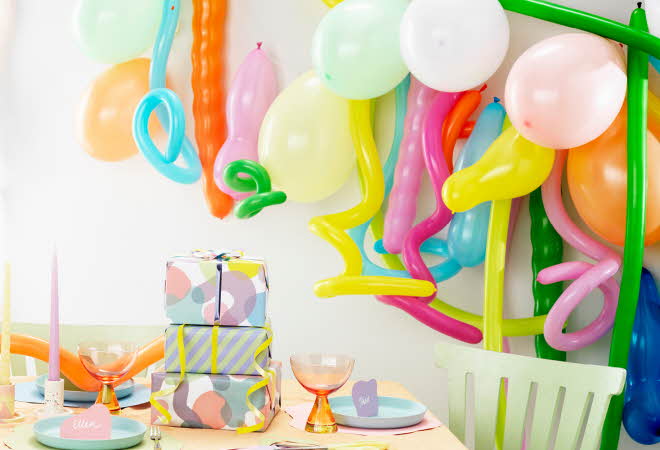 Fargerik festoppsett med ballonger og innpakkede gaver på et dekorert bord.
