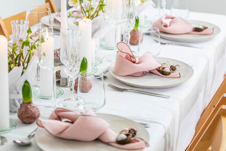 Langbord dekker til gjester med rosa servietter og grønn naturlig dekorasjon
