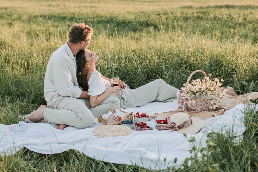 Dame og mann som har piknik i en eng