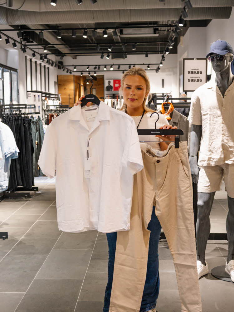 dame holder klessplagg til herre i butikk