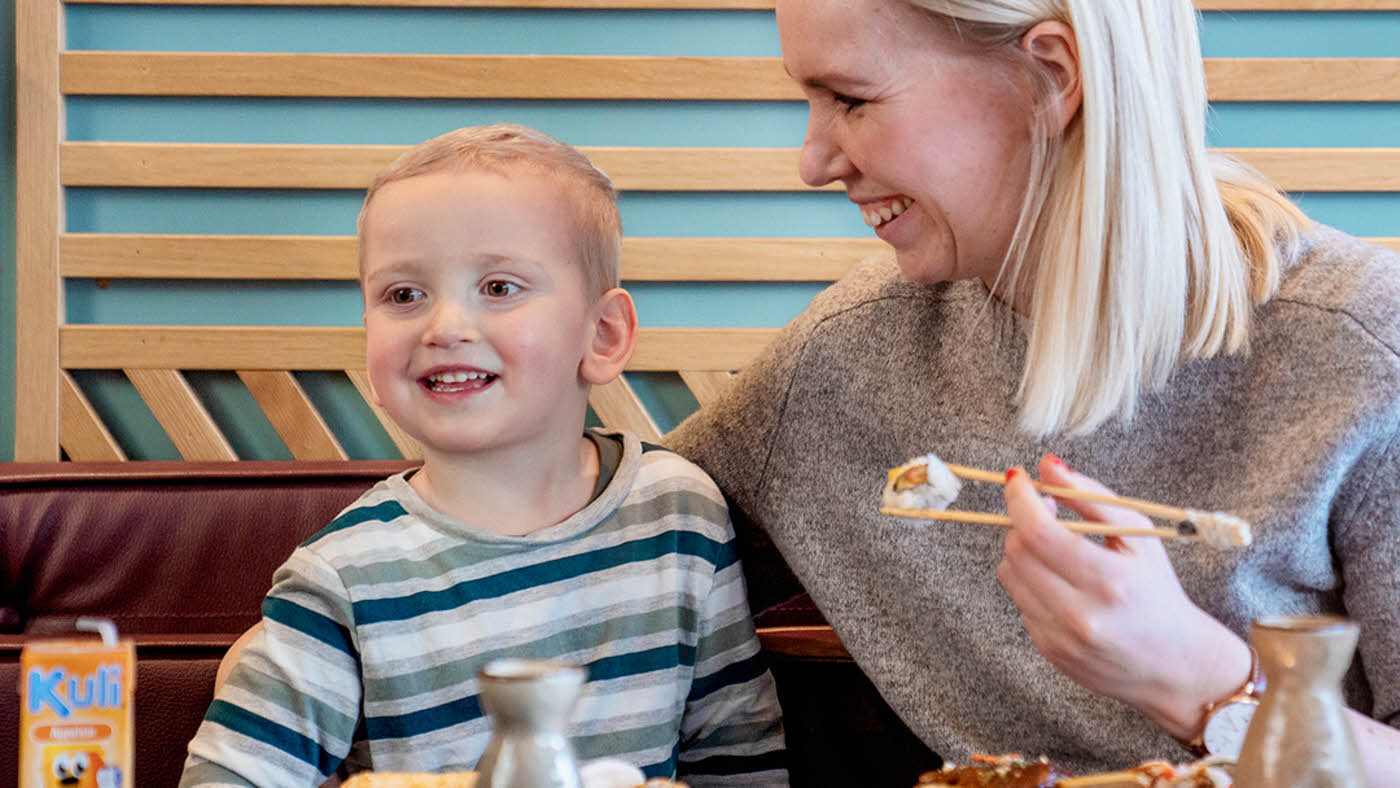 mor og sønn spiser på restaurant med godt humør