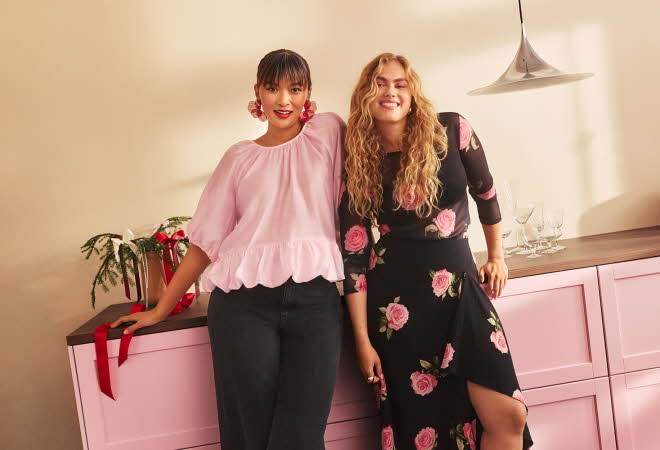 To kvinner står og lener seg på en rosa kjøkkenbenk