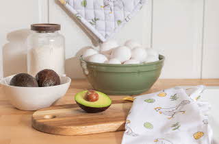 En grønn bolle med egg og en hvit bolle med to avokadoer