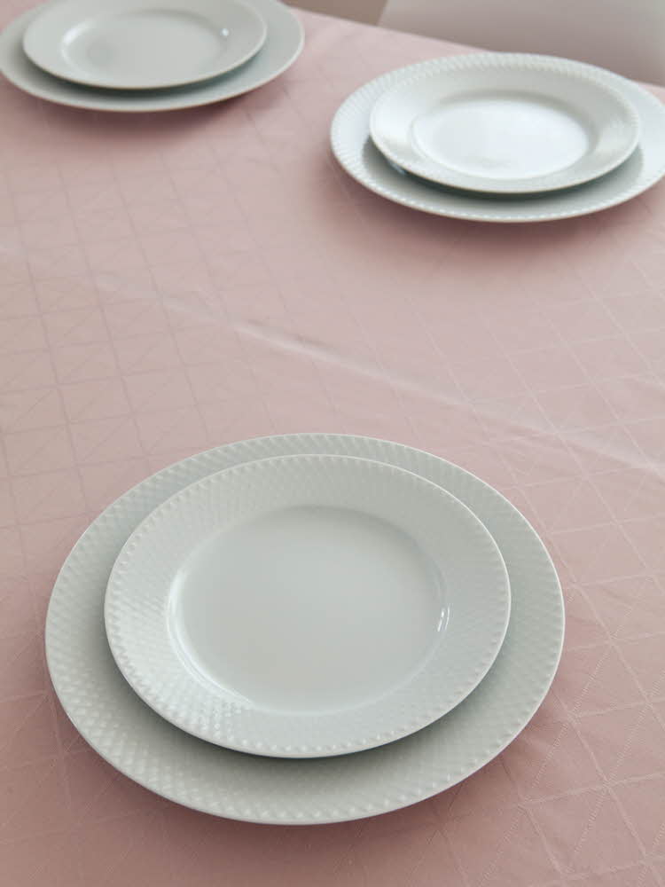 Steg en - Bord dekket med tallerkener på en rosa duk  Steg 2 - Bord dekket med tallerkener og hvit linservietter på en rosa duk 