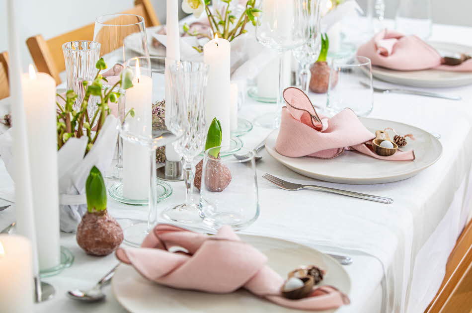 Langbord dekker til gjester med rosa servietter og grønn naturlig dekorasjon