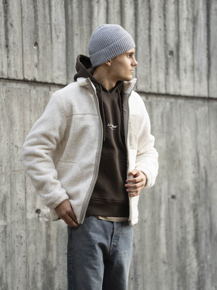 Gutt i grå lue, hvit fleecejakke, brun hettegenser og jeans.