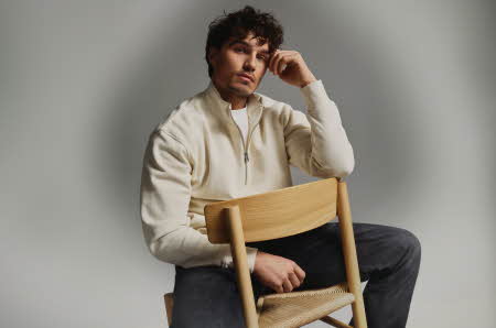 En mann i en beige genser som sitter baklengs på en stol