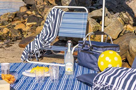 sitteplass på stranden med lenestol, kjølebag, sitteunderlag og teppe i stripete mønster