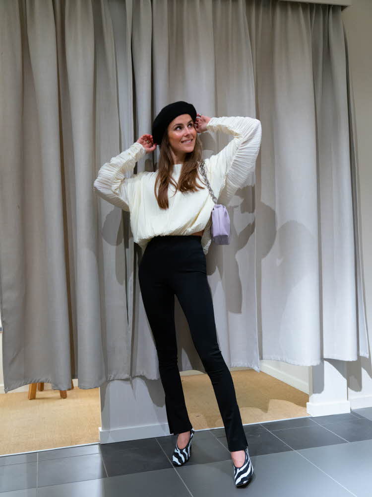 Nina Sandbech på H&M i hvit genser, sort bukse og lilla veske