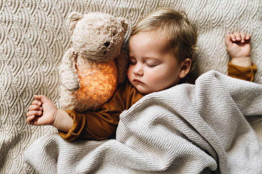 Barn med bamse som sover