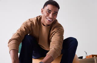 En mann som sitter på en gul treningsball i uformelt antrekk.