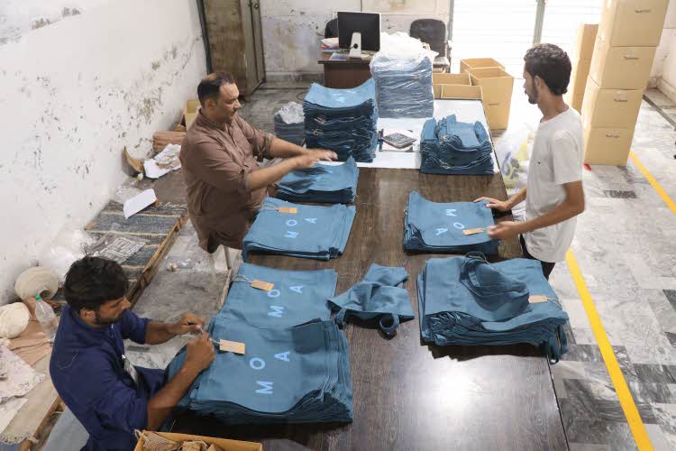 Ansatte på fabrikken syr og stryker poser