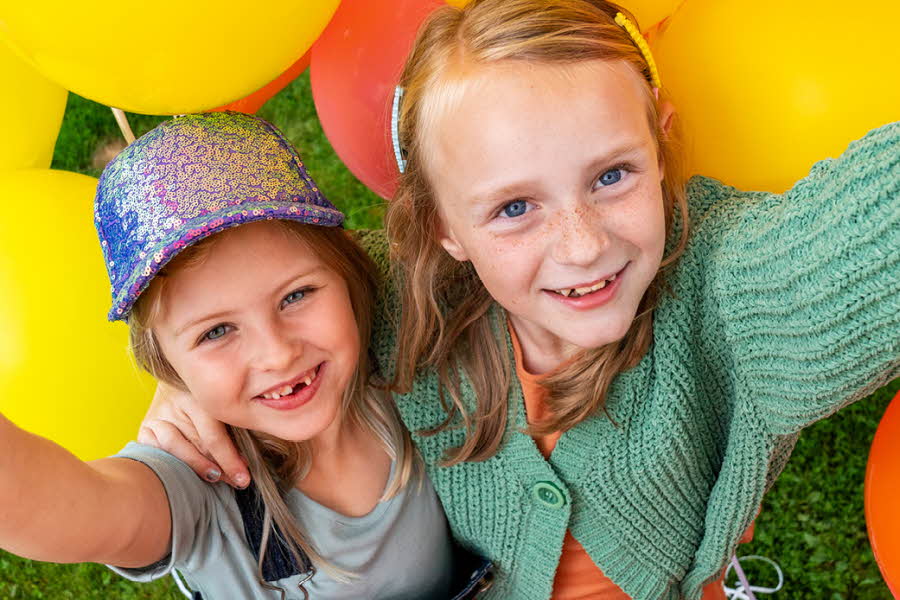 to barn smiler ved siden av fargerike ballonger