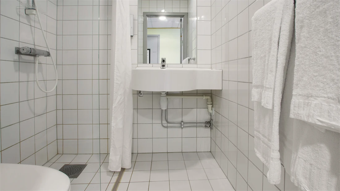 Bad med toalett, dusj, vask og speil på Standard room queen på Thon Hotel Horten