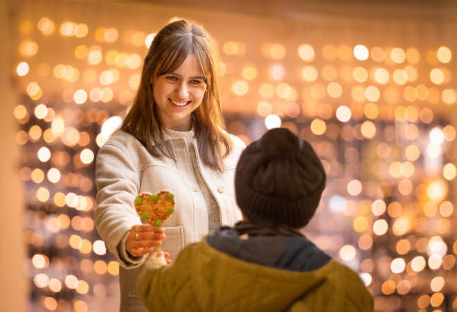 Dame som gir pepperkakehjerte til en gutt