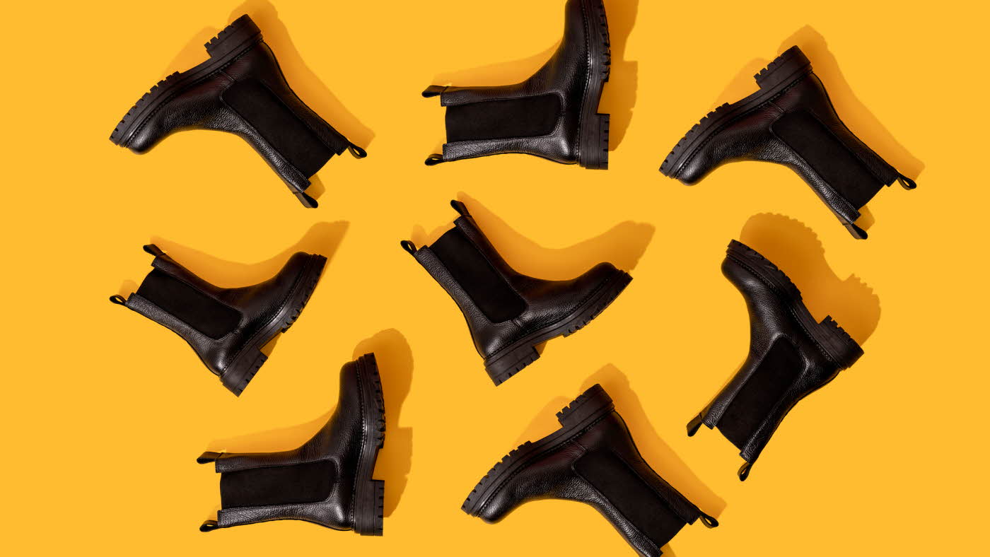 Svarte Chelsea-boots på oransje underlag i studio.