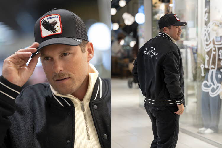 Mann i caps, blå baseball-jakke, hvit genser og jeans.