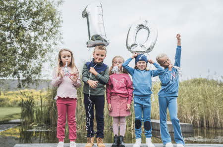Barn som smiler og holder to ballonger