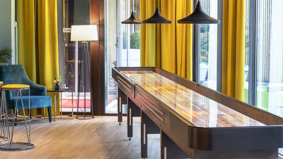 Shuffleboard, store vinduer og gule gardiner i lobbyen på Thon Hotel Maritim