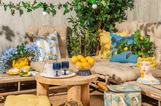 Et uteområde med to sofaer og et lite bord. Sofaene har mange fine pynteputer i forskjellige farger og mønster