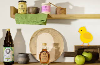 Kjøkkenhylle med eplecidereddik, lønnesirup, grønne epler og en gul kyllingillustrasjon.
