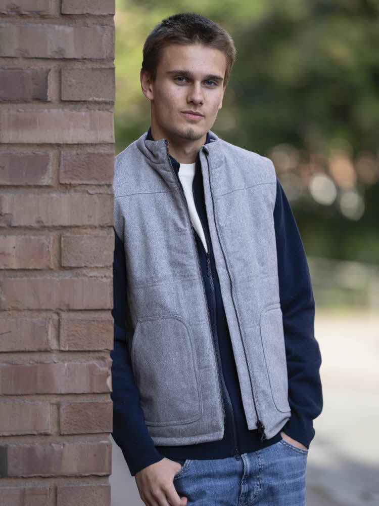 Gutt i jeans, blå strikkejakke, hvit t-skjorte og grå vest.