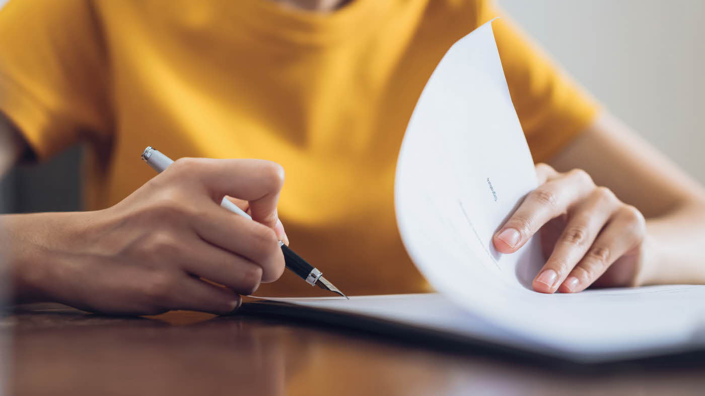 Dame i gul t-skjorte signerer ark