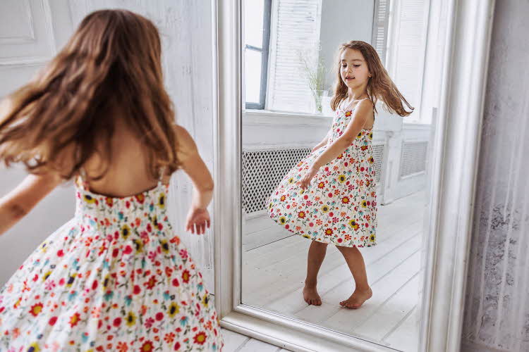 Jente danser i blomstrete kjole foran speilet