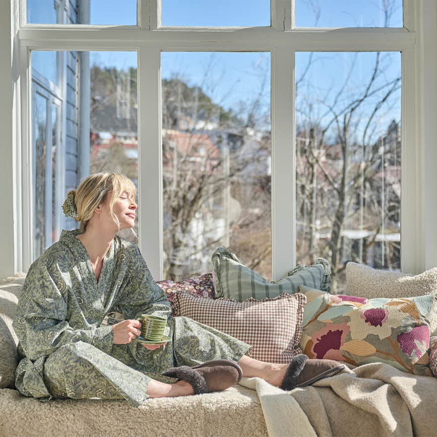 Dame som nyter solen i en vinterhage