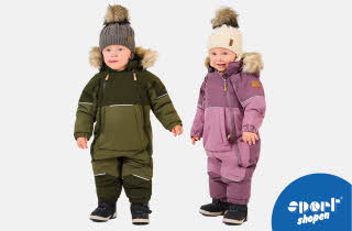 To barn står i vinterdresser med pelskant på hetten og varme støvler.