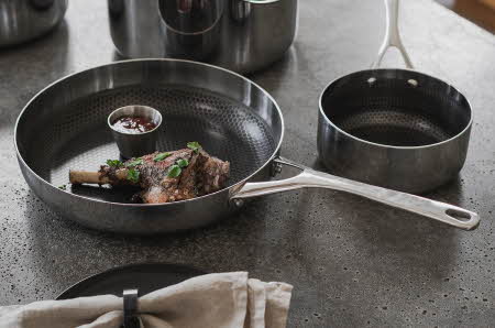 En stekepanne og en kjele som står ved siden av hverandre. Stekepannen har mat i seg.