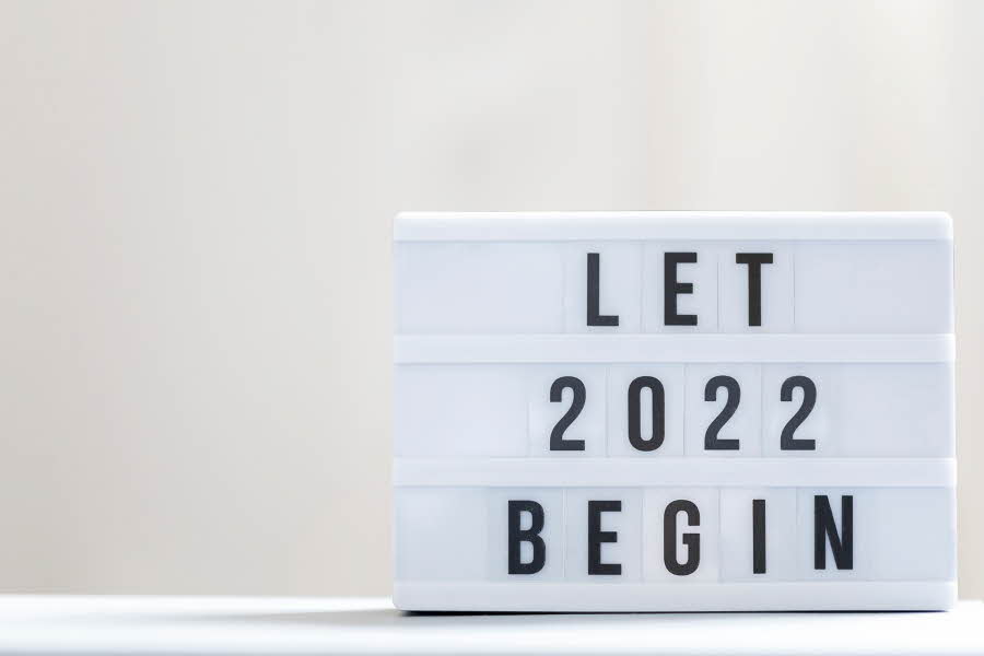 Hvit figur med sort tekst: Let 2022 begin. Hvitt underlag og lysegrå bakgrunn.