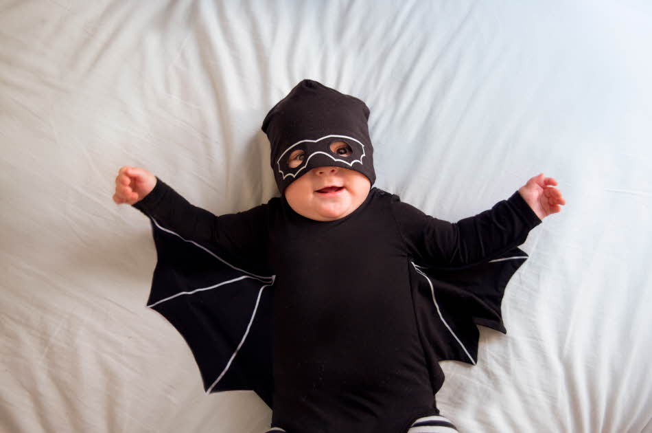 Baby som ligger i et svart flaggermus kostyme