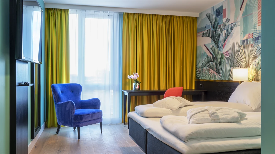 Dobbeltseng god gulvplass, smart tv, lenestol og arbeidspult med friske farger på Thon Hotel Storo i Oslo