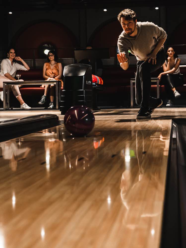 lysende rundt skilt i taket mann som kaster bowlingkule på bowlingbane mann og dame som synger karaoke