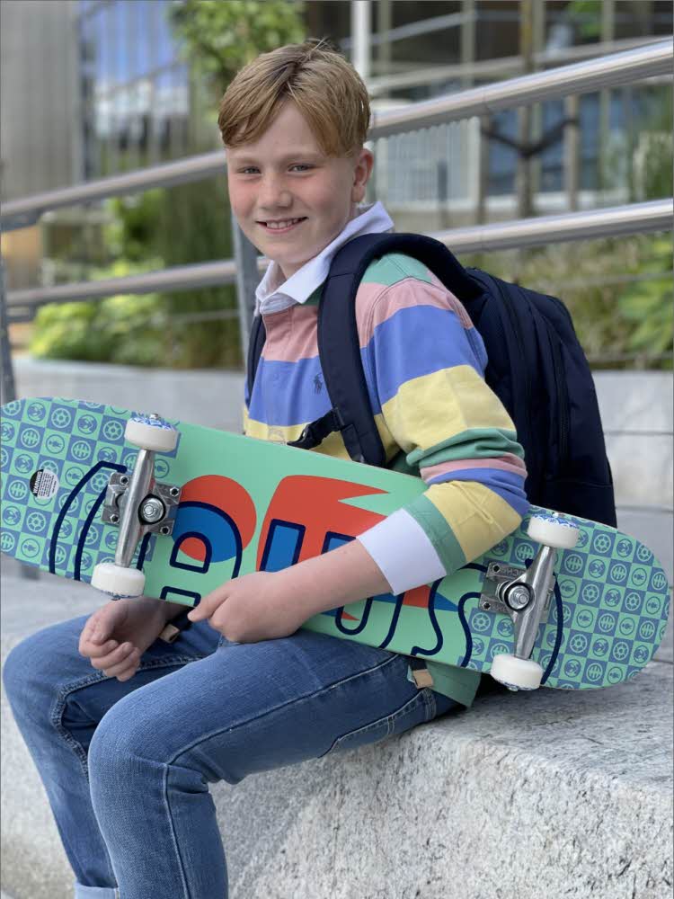Gutt sitter på en mur og holder et skateboard