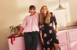 To kvinner står og lener seg på en rosa kjøkkenbenk