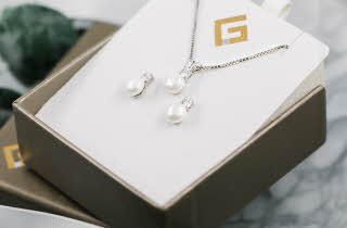 En smykkeeske med et smykke og et par øredobber med perler