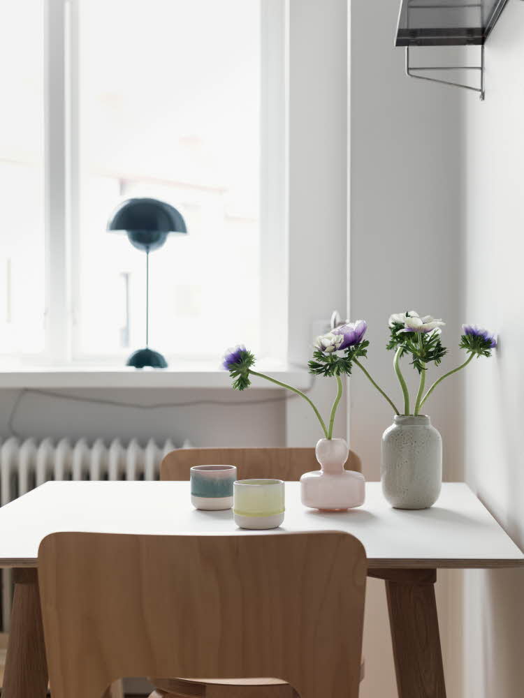 Spisebord med trestoler og mørk blå flowerpotlampe i vinduskarmen