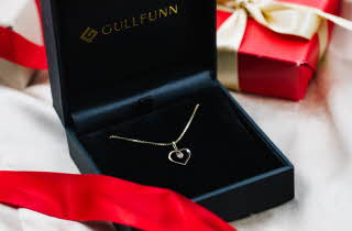 Et gullsmykke med hjerte anheng som ligger i en Gullfunn boks