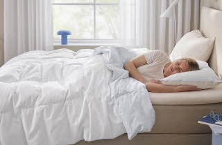 bilde av en dame som sover i en seng med heatflex dyne