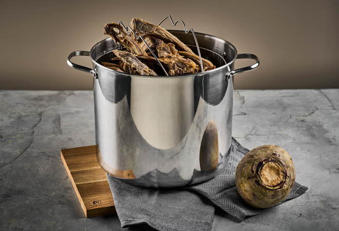 En pinnekjøttgryte med pinnekjøtt i står på en benk.