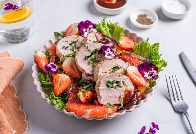 Tallerken med salat, inkludert kjøtt, jordbær, grapefrukt, salatblader og spiselige blomster.