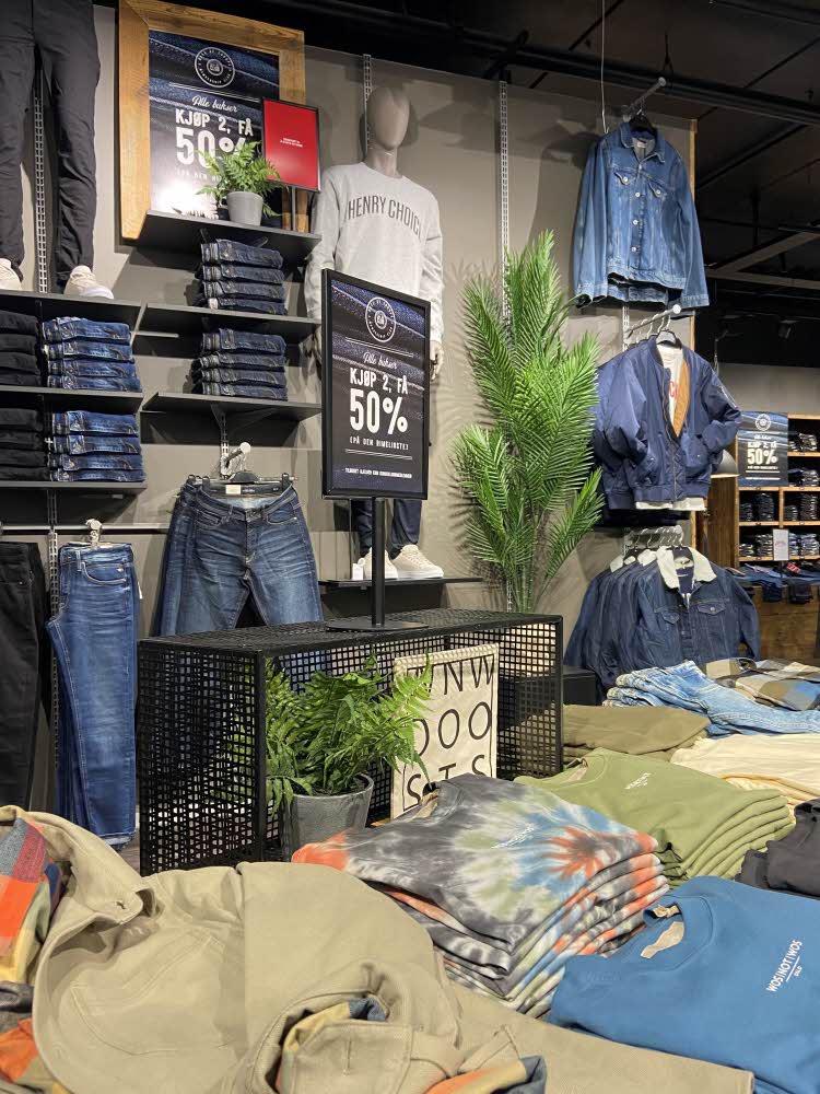 Inne i butikken Boys of Europe, et bord med fargerike overdeler og en bakvegg med blå jeans