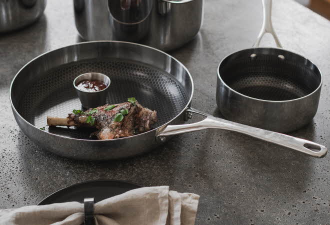 En stekepanne og en kjele som står ved siden av hverandre. Stekepannen har mat i seg.