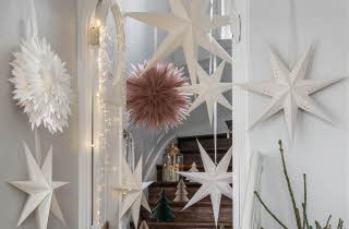 Hvite og rosa papirstjerner henger i en trappoppgang.