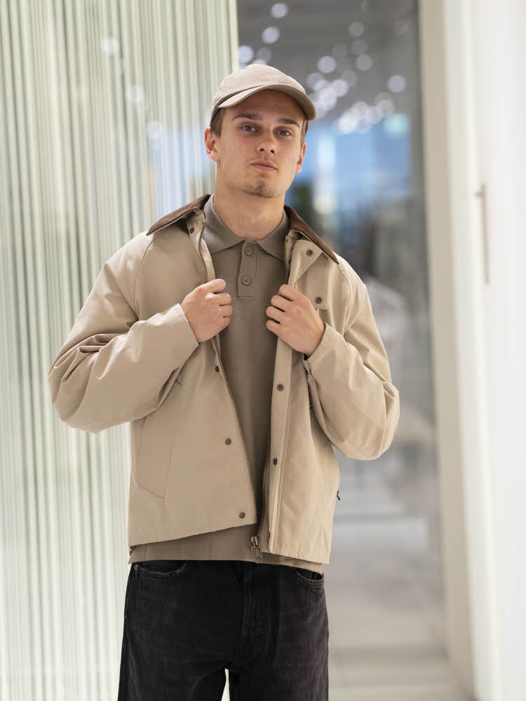 Gutt i beige caps, beige jakke, brun genser og sorte bukser.