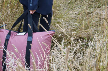 Person med rosa bag i en eng av strå