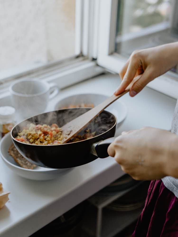 en som holder stekepanne med mat
